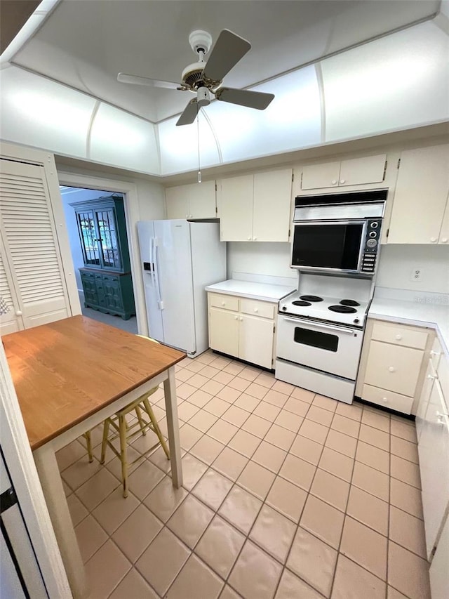 4950 Gulf Blvd Unit 404, St Pete Beach, FL 33706 - kitchen featuring white appliances, light tile patterned floors, light countertops, a ceiling fan, and white cabinetry