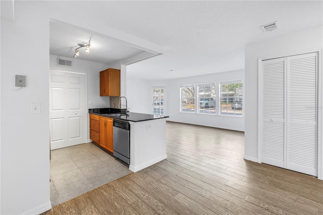 3305 Haviland Ct Unit 101, Palm Harbor, FL 34684 - kitchen with stainless steel dishwasher, dark countertops, brown cabinets, a peninsula, and open floor plan
