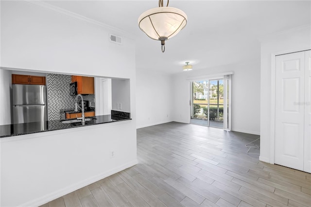 3300 Haviland Ct Unit 103, Palm Harbor, FL 34684 - kitchen with freestanding refrigerator, brown cabinets, crown molding, light wood finished floors, and tasteful backsplash