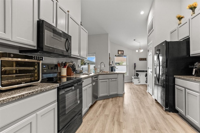 2053 Charleston Ln, Bartow, FL 33830 - kitchen featuring black appliances, light wood-style floors, a peninsula, lofted ceiling, and a sink