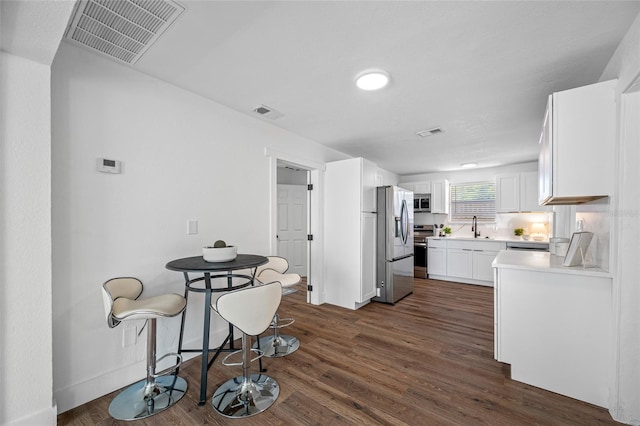 4626 8th Ave S, Saint Petersburg, FL 33711 - kitchen with appliances with stainless steel finishes, a sink, white cabinets, light countertops, and dark wood finished floors