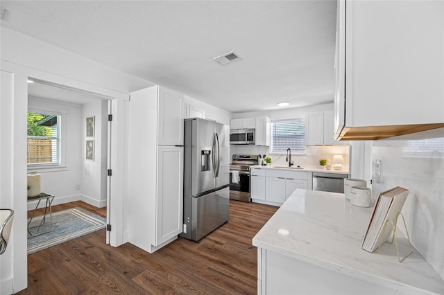 4626 8th Ave S, Saint Petersburg, FL 33711 - kitchen with appliances with stainless steel finishes, a sink, white cabinetry, dark wood-style flooring, and light stone counters