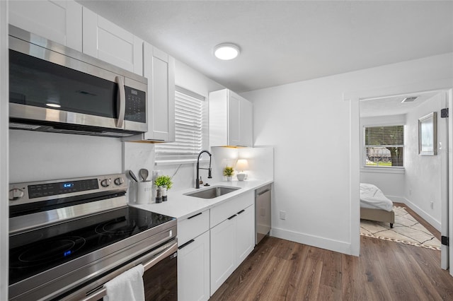 4626 8th Ave S, Saint Petersburg, FL 33711 - kitchen featuring appliances with stainless steel finishes, a sink, dark wood-type flooring, white cabinetry, and light countertops