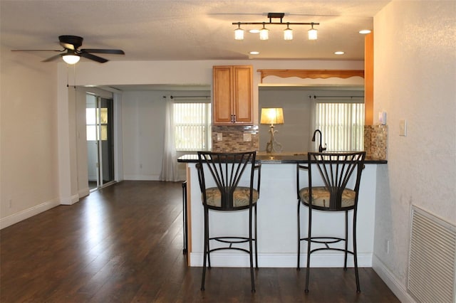 9705 45th Way N, Pinellas Park, FL 33782 - kitchen with a breakfast bar area, ceiling fan, dark countertops, dark wood finished floors, and healthy amount of natural light
