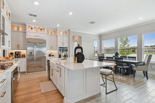 6129 Marsh Trail Dr, Odessa, FL 33556 - kitchen featuring appliances with stainless steel finishes, arched walkways, crown molding, light wood-style floors, and light countertops