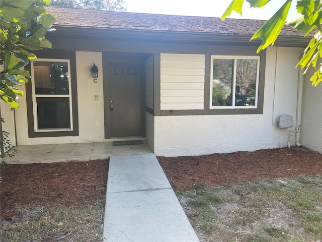 2160 Corbin Pl Unit C, Palm Harbor, FL 34683 - view of exterior entry featuring roof with shingles, stucco siding, and covered porch