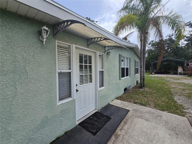 4352 Joy Dr, Land O Lakes, FL 34638 - property entrance with stucco siding and a detached carport