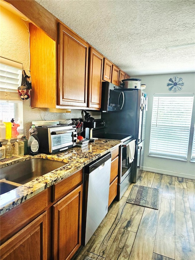 4352 Joy Dr, Land O Lakes, FL 34638 - kitchen with stainless steel dishwasher, electric range, plenty of natural light, a textured ceiling, and light wood-style flooring