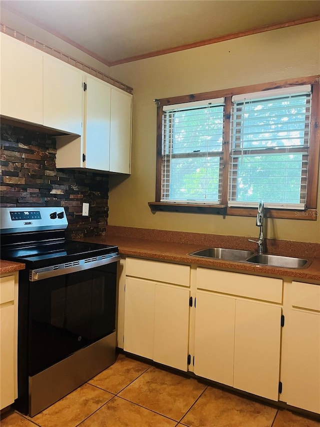 9907 Maggie St, Gibsonton, FL 33534 - kitchen featuring electric stove, a sink, backsplash, light tile patterned floors, and white cabinetry