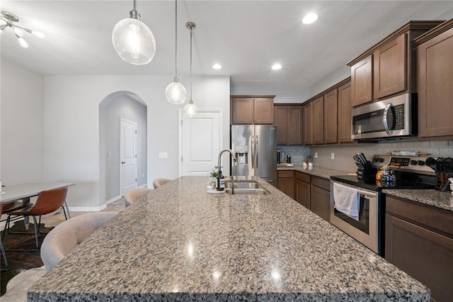4504 Silver Lining St, Sarasota, FL 34238 - kitchen featuring appliances with stainless steel finishes, arched walkways, a kitchen island with sink, decorative backsplash, and recessed lighting