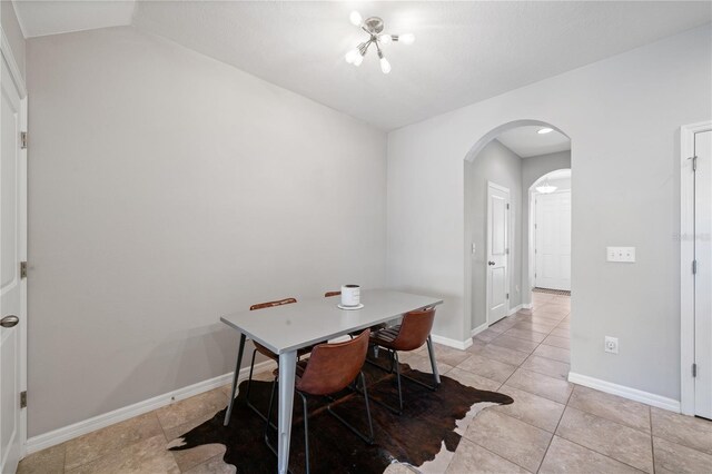 4504 Silver Lining St, Sarasota, FL 34238 - dining space featuring arched walkways, light tile patterned floors, baseboards, vaulted ceiling, and a chandelier