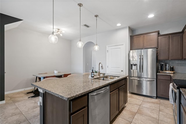 4504 Silver Lining St, Sarasota, FL 34238 - kitchen featuring stainless steel appliances, a sink, dark brown cabinets, decorative backsplash, and light stone counters