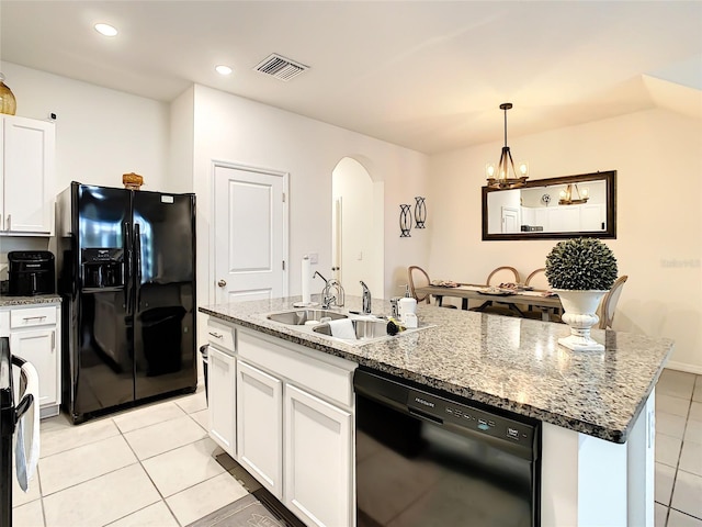 32977 Kaloko Rd, Wesley Chapel, FL 33543 - kitchen with black appliances, arched walkways, light tile patterned flooring, a center island with sink, and white cabinetry