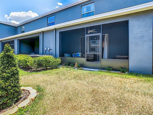 32977 Kaloko Rd, Wesley Chapel, FL 33543 - back of house featuring stucco siding, a sunroom, and a lawn