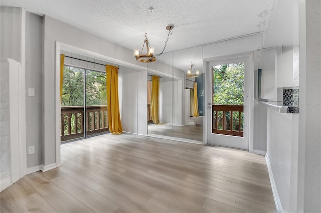 1038 E Michigan St Unit B, Orlando, FL 32806 - unfurnished dining area with a chandelier, a textured ceiling, light wood-type flooring, and baseboards
