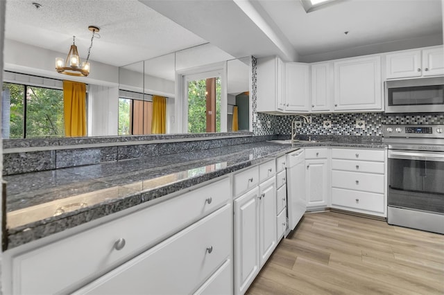 1038 E Michigan St Unit B, Orlando, FL 32806 - kitchen with appliances with stainless steel finishes, white cabinetry, tasteful backsplash, light wood finished floors, and a sink