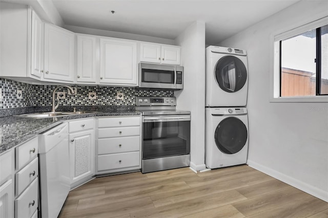 1038 E Michigan St Unit B, Orlando, FL 32806 - kitchen featuring appliances with stainless steel finishes, stacked washer / dryer, a sink, and white cabinetry