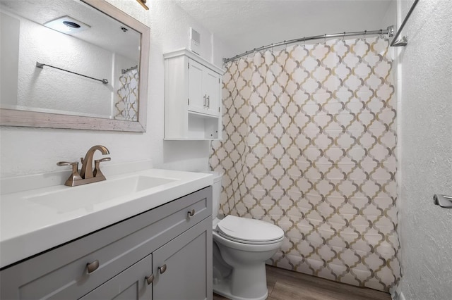 1038 E Michigan St Unit B, Orlando, FL 32806 - bathroom featuring vanity, toilet, wood finished floors, a textured wall, and curtained shower