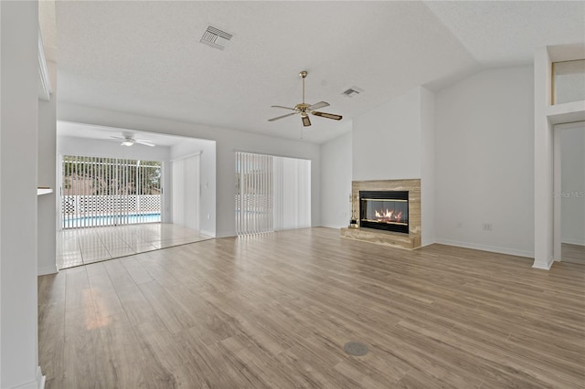 11411 Terrell, Spring Hill, FL 34606 - unfurnished living room featuring a ceiling fan, light wood finished floors, a glass covered fireplace, vaulted ceiling, and baseboards