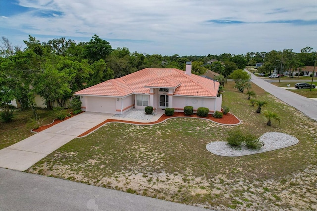 11411 Terrell, Spring Hill, FL 34606 - mediterranean / spanish house featuring concrete driveway, a tile roof, an attached garage, a chimney, and a front lawn
