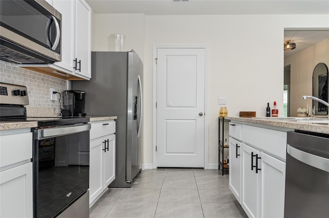 33668 Elm Hill Br, Wesley Chapel, FL 33545 - kitchen with stainless steel appliances, tasteful backsplash, white cabinets, light tile patterned floors, and baseboards