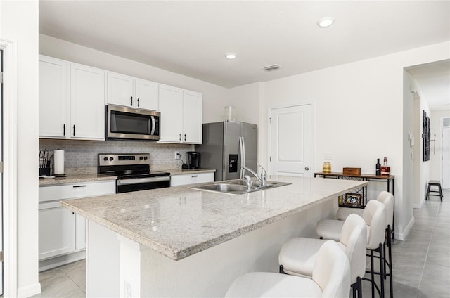 33668 Elm Hill Br, Wesley Chapel, FL 33545 - kitchen featuring stainless steel appliances, backsplash, white cabinetry, a kitchen bar, and recessed lighting