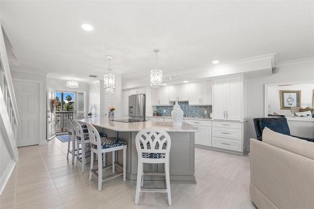 433 S Paula Dr Unit 31, Dunedin, FL 34698 - kitchen with stainless steel fridge, crown molding, a kitchen breakfast bar, white cabinetry, and a spacious island