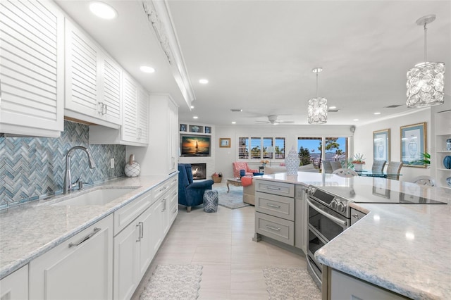433 S Paula Dr Unit 31, Dunedin, FL 34698 - kitchen featuring stainless steel range with electric stovetop, open floor plan, a glass covered fireplace, tasteful backsplash, and recessed lighting