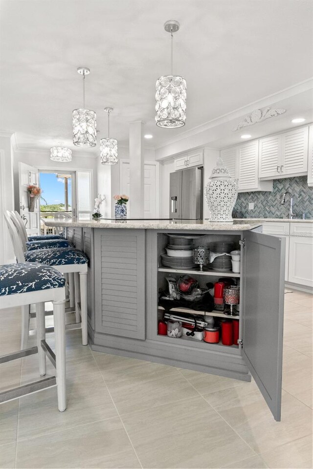 433 S Paula Dr Unit 31, Dunedin, FL 34698 - kitchen with stainless steel refrigerator with ice dispenser, a chandelier, backsplash, white cabinetry, and crown molding