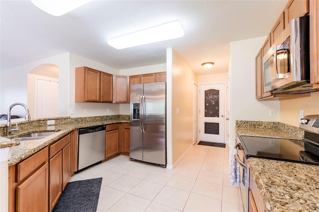 12624 White Bluff Rd, Hudson, FL 34669 - kitchen featuring appliances with stainless steel finishes, a sink, light stone countertops, light tile patterned floors, and brown cabinets