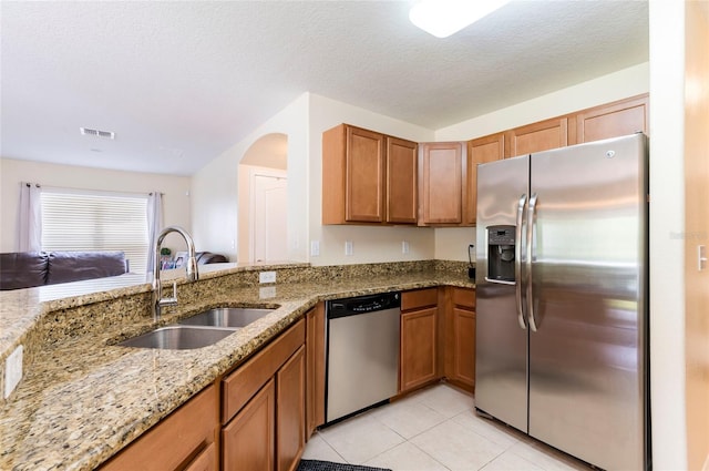 12624 White Bluff Rd, Hudson, FL 34669 - kitchen featuring appliances with stainless steel finishes, a sink, light stone counters, brown cabinetry, and a textured ceiling