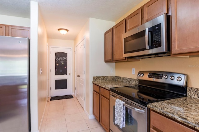 12624 White Bluff Rd, Hudson, FL 34669 - kitchen with appliances with stainless steel finishes, brown cabinets, light tile patterned floors, and dark stone countertops