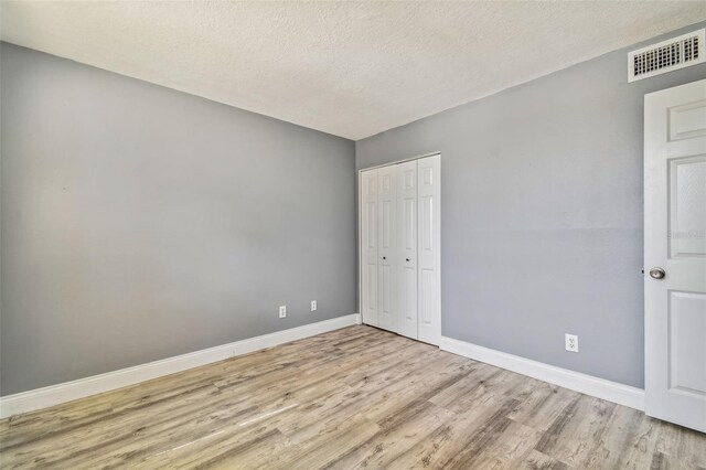 1967 Cormorant Ct Unit 515, Clearwater, FL 33762 - unfurnished bedroom with wood finished floors, baseboards, a closet, and a textured ceiling