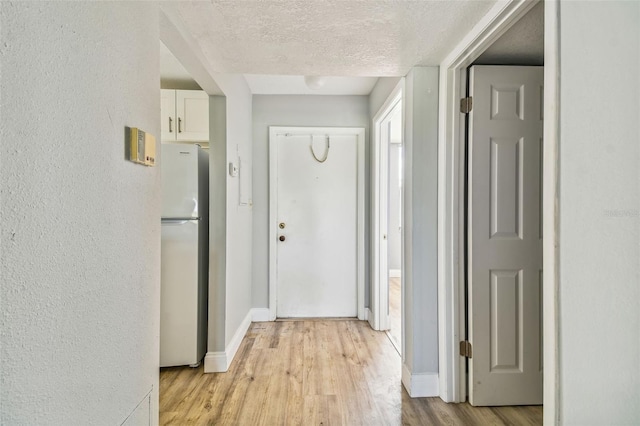 1967 Cormorant Ct Unit 515, Clearwater, FL 33762 - corridor featuring light wood finished floors, a textured ceiling, baseboards, and a textured wall