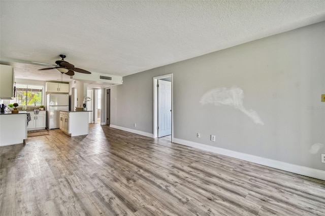 1967 Cormorant Ct Unit 515, Clearwater, FL 33762 - unfurnished living room with a textured ceiling, wood finished floors, a ceiling fan, and baseboards