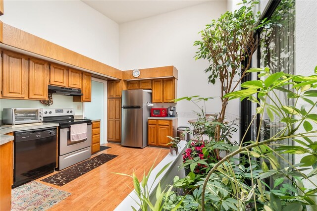 70 Morning Dove Pl, Oldsmar, FL 34677 - kitchen with appliances with stainless steel finishes, under cabinet range hood, a high ceiling, light wood-style floors, and brown cabinetry