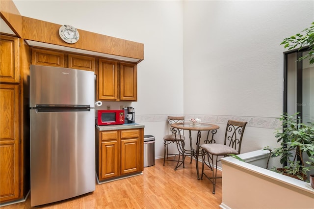 70 Morning Dove Pl, Oldsmar, FL 34677 - kitchen featuring freestanding refrigerator, brown cabinets, white microwave, and light wood finished floors