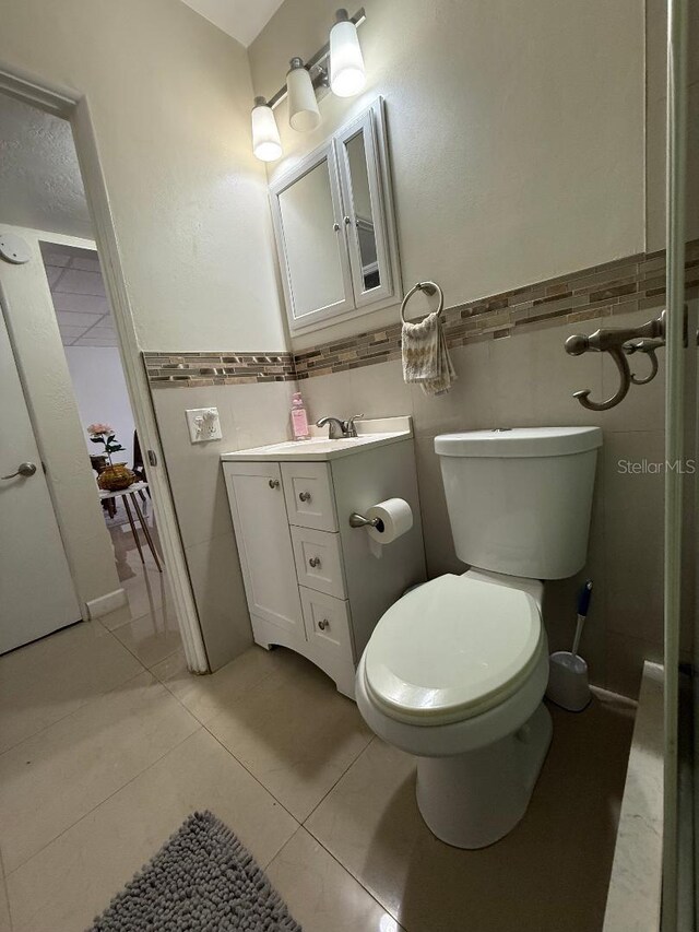 5860 43rd Ter N Unit 1518, Kenneth City, FL 33709 - bathroom featuring tile walls, vanity, toilet, a wainscoted wall, and tile patterned flooring
