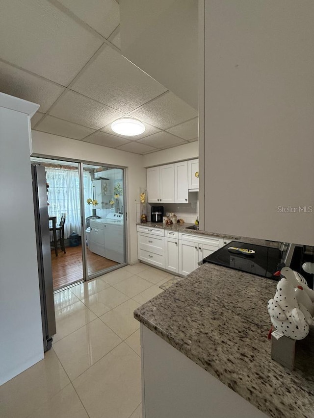 5860 43rd Ter N Unit 1518, Kenneth City, FL 33709 - kitchen with washing machine and clothes dryer, a paneled ceiling, white cabinets, freestanding refrigerator, and light tile patterned floors