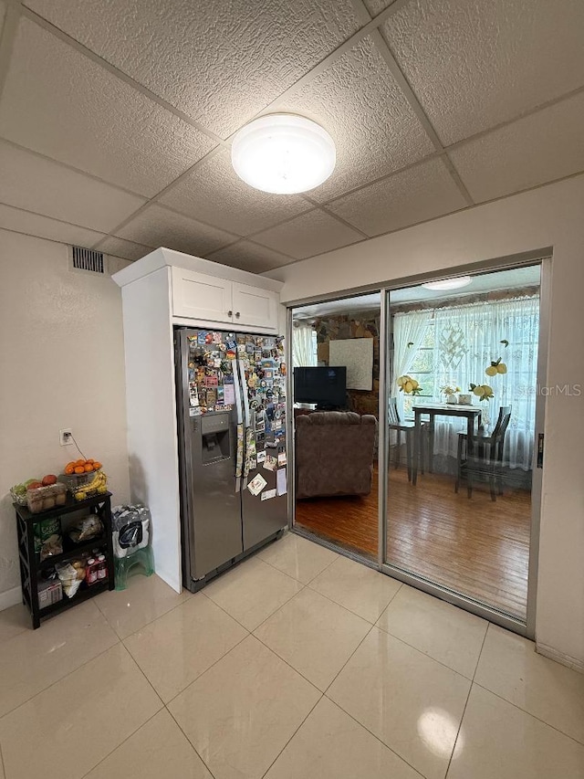 5860 43rd Ter N Unit 1518, Kenneth City, FL 33709 - kitchen featuring stainless steel fridge with ice dispenser, a paneled ceiling, white cabinets, and light tile patterned flooring