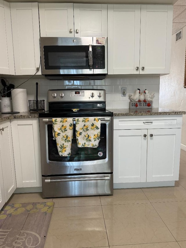 5860 43rd Ter N Unit 1518, Kenneth City, FL 33709 - kitchen featuring stainless steel appliances, backsplash, white cabinets, dark stone countertops, and light tile patterned floors