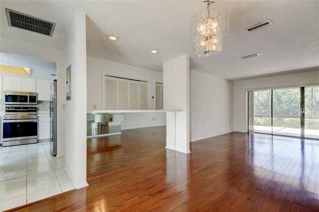 50 Ingrid Pl Unit 50, Oldsmar, FL 34677 - unfurnished living room featuring light wood-type flooring, a chandelier, and recessed lighting