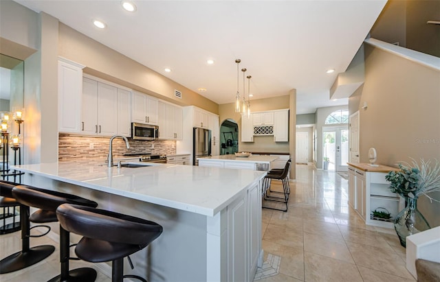 1710 Lago Vista Blvd, Palm Harbor, FL 34685 - kitchen with stainless steel appliances, tasteful backsplash, a peninsula, a breakfast bar area, and white cabinetry