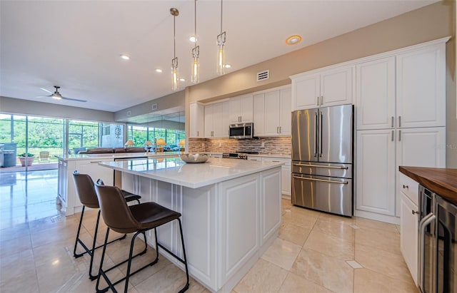 1710 Lago Vista Blvd, Palm Harbor, FL 34685 - kitchen with stainless steel appliances, wine cooler, a center island, decorative backsplash, and light tile patterned floors