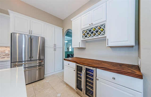 1710 Lago Vista Blvd, Palm Harbor, FL 34685 - kitchen featuring freestanding refrigerator, butcher block counters, beverage cooler, light tile patterned floors, and white cabinets
