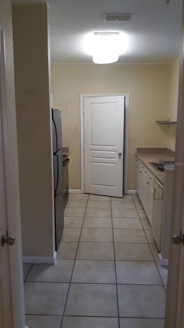 9320 Crescent Loop Cir Unit 304, Tampa, FL 33619 - kitchen with white cabinets, dishwasher, freestanding refrigerator, light tile patterned flooring, and baseboards