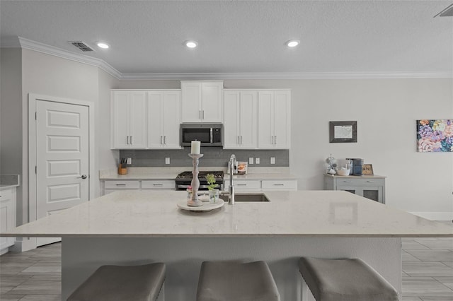 4077 Cadence Loop, Land O Lakes, FL 34638 - kitchen with stainless steel appliances, a kitchen bar, crown molding, tasteful backsplash, and white cabinets