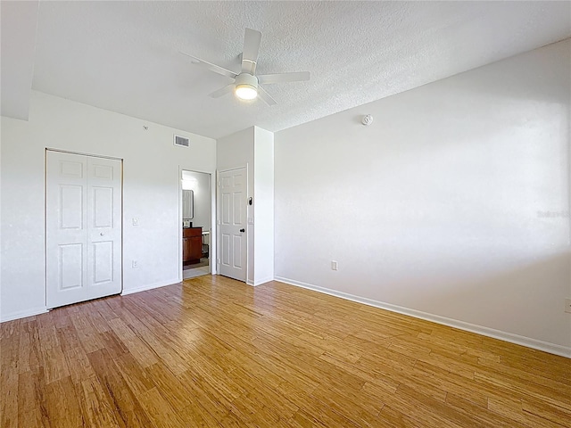 2015 SE 10th Ave Unit 123, Fort Lauderdale, FL 33316 - unfurnished bedroom featuring light wood-style floors, ensuite bathroom, a ceiling fan, and a textured ceiling