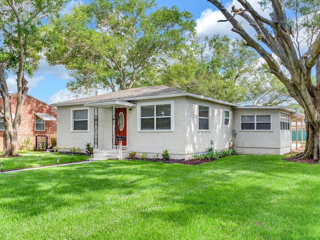 1243 55th Ave N, Saint Petersburg, FL 33703 - view of front of house with stucco siding, a front yard, and a shingled roof