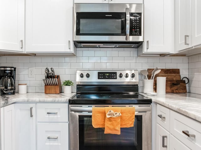 1243 55th Ave N, Saint Petersburg, FL 33703 - kitchen featuring appliances with stainless steel finishes, white cabinets, backsplash, and light stone countertops